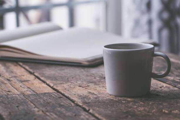 Notebook, cup of tea, and a calm workspace on a porch in Austin, TX representing sustainable productivity for a professional woman.