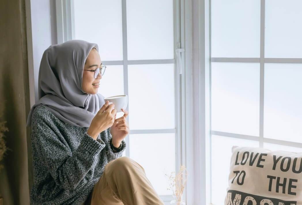 Professional woman in her 30s, reflecting in a window in Austin, TX, symbolizing a shift from harsh self-criticism to a healthier self-perspective.
