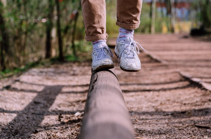 Professional woman in her 30s standing at a fork in the road in Austin, TX symbolizing new habits as she tries to find balance while feeling on edge.